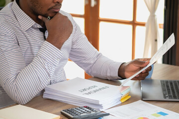 Wall Mural - African black businessman sitting doing a financial report and studying annual profit analysis An accountant checking the financial status of the company is in the office.