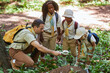 © Seventyfour - Diverse group of scouts inspecting anthill with magnifying glass while exploring nature during field trip