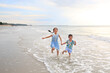 © zilvergolf - Happy Asian girl kid and little boy having fun running on tropical sand beach at sunrise. Happy family sister and brother enjoy in summer holiday.