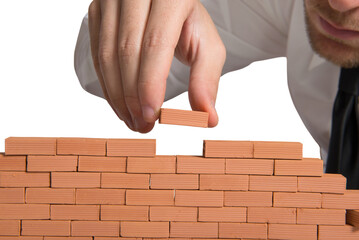 businessman puts a piece of brick to build a wall