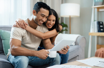 Poster - He knows me all too well. a young couple sitting on the sofa together at home and using a digital tablet.
