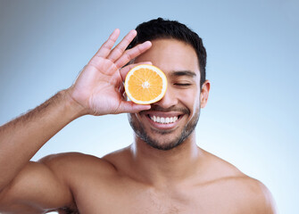 Poster - My skincare, my journey. Studio shot of a handsome young man posing with an orange against a grey background.