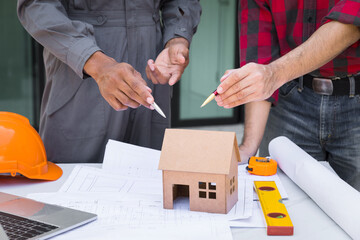 Wall Mural - House model on desk over confident team of architects working together in a office. Architect discuss with engineer about project in office, architectural concept.