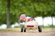 kleines Mädchen im Blechauto im Park