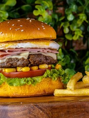 Poster - Delicious cheeseburger served with freshly-sliced tomatoes and corn on the cob, on a tabletop