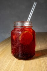 Sticker - Canning jar filled with red tasty lemonade with a straw on a table top