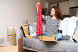 © Barillo Images - Curly woman unpacking parcel with her new summer dress online purchase from internet store.