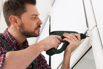 Canvas Print - Worker in uniform installing roller window blind indoors