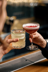 Close up of two people cheering cocktails in a bar or disco club drinks and cocktails concept