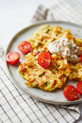 Wall Mural - Snack waffles with bacon, cheddar cheese, spinach, sauce and cherry tomatoes on light background