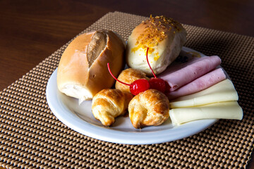 Plate with two breads, slices of cheese and ham and croissant