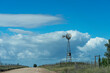 Argentinian countryside landscape, rural road and windmill, with clouds in the background