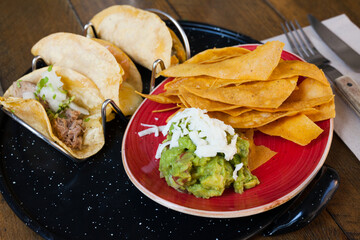 Wall Mural - Delicious Mexican set of tacos with carnitas, shrimps and corn and crispy nachos with guacamole