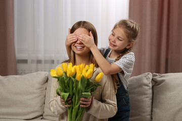 Sticker - Little daughter congratulating mom with bouquet of yellow tulips at home. Happy Mother's Day