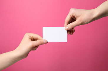 Women holding blank gift card on pink background, closeup