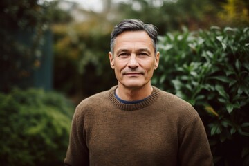 Wall Mural - Portrait of handsome middle-aged man in brown sweater standing outdoors