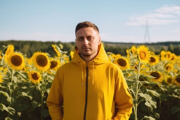 Portrait of a young man in a yellow jacket standing in a sunflower field.