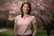 © Robert MEYNER - Beautiful young woman in a pink shirt standing in front of a blooming cherry tree.
