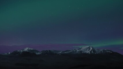 Wall Mural - Northern Lights (Aurora Borealis) shining above snowy mountain peaks on a starry night sky. Time Lapse.