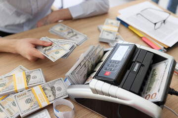 Woman uses bill counter to count money after profitable deal