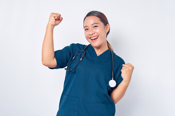 Wall Mural - Excited young Asian female professional nurse working wearing a blue uniform standing confident while saying yes and celebrating victory isolated on white background. Healthcare medicine concept