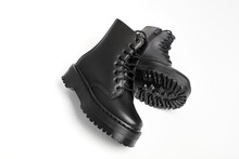 Black Women Combat Boots On High Heel Platform With Lug Soles Lying On Isolated White Background. Military Stylish High Heel Platform Combat Boots For Woman Legs, New Footwear Trends