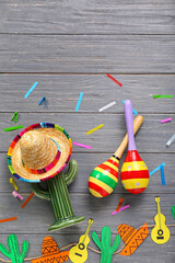 Wall Mural - Mexican maracas with sombrero hat, cactus and garland on dark wooden background