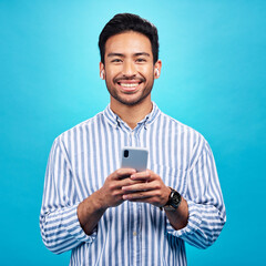 Poster - happy, portrait and a man with a phone for communication isolated on a blue background in a studio. 