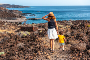 Wall Mural - Mother and son on vacation walking on a path along the beach of Tacoron on El Hierro, Canary Islands