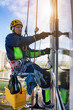 Professional industrial mountaineering worker washing exterior facade glazing, hanging over building. Rope access laborer climbing on wall of skyscraper. Urban works concept. Copy text space for ad