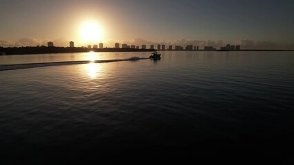 Wall Mural - Aerial of a boat sailing in the calm ocean at North Palm Beach, Florida during the golden sunset