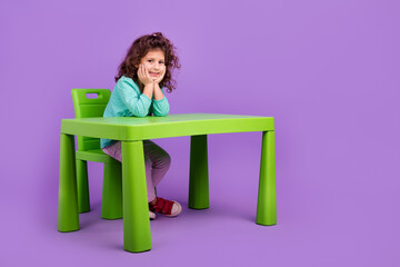 Wall Mural - Full length photo of shiny cute little child dressed teal shirt sitting table studying empty space isolated purple color background