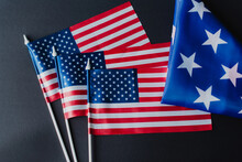 Top View Of Three American Flags Near Folded Fabric With Stars During Memorial Day Isolated On Black.