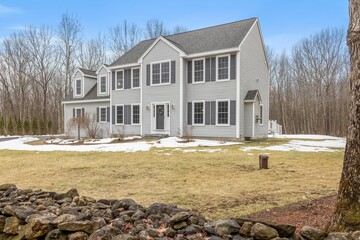 Modern colonial home in central New England surrounded by bared trees in wintertime