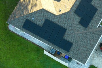 Wall Mural - Ordinary residential house in USA with rooftop covered with solar photovoltaic panels for producing of clean ecological electrical energy in suburban rural area. Concept of autonomous home