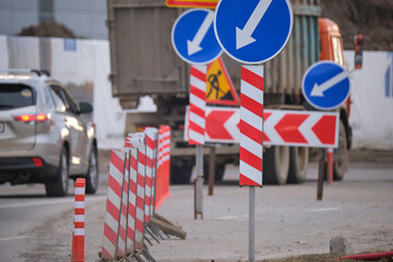 roadworks warning traffic signs of construction work on city street and slowly moving cars