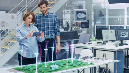 Wall Mural - green energy concept: two ecological engineers use augmented reality smartphone to design 3d wind tu