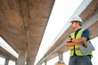 © เลิศลักษณ์ ทิพชัย - Asian civil engineer specialists examining trades at road construction site, industrial building construction site. Concrete skyscraper of road construction