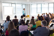 © kasto - Business and entrepreneurship symposium. Speaker giving a talk at business meeting. Audience in conference hall. Rear view of unrecognized participant in audience.