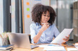 © Tj - Female Entrepreneur. Cheerful African American Businesswoman Working On document and Laptop In Modern Office. Empty Space