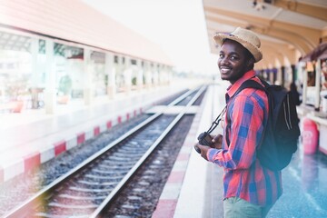 Wall Mural - African backpackers wearing hats and cameras waiting for a train at a station to travel.Adventure travel concept