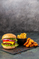 Wall Mural - Homemade delicious sandwich fries chicken nuggets on black board fries pepper on dark gray blurred background