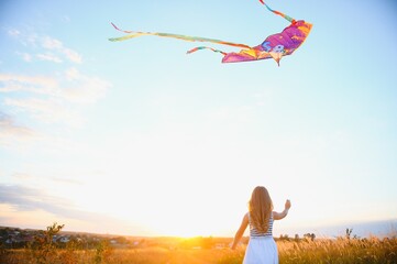 Wall Mural - happy child girl with a kite running on meadow in summer in nature