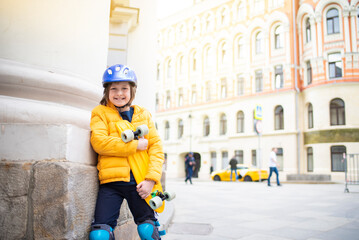 Wall Mural - portrait of happy schoolboy in purple helmet, yellow jacket holding yellow urban cruiser, skateboard.