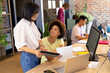 © Wavebreak Media - Two happy diverse female creative colleagues using tablet and discussing at desk in busy office