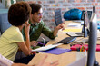 © Wavebreak Media - Two diverse creative colleagues using computer discussing project at desk in casual office