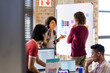 © Wavebreak Media - Happy diverse designers discussing project at whiteboard in busy casual office