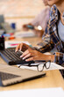 © Wavebreak Media - Midsection of biracial casual businesswoman working on computer, with glasses on desk in office