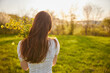 photo from the back of a red-haired woman with a bouquet of flowers in the rays of the setting sun