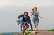 © Igor - Positive young man riding on longboard while his girlfriend running near him against gray sky